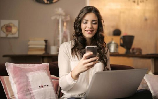 Ragazza davanti al pc guarda lo smartphone