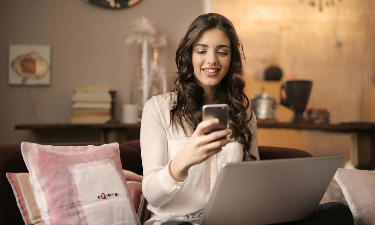 Ragazza davanti al pc guarda lo smartphone