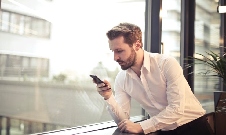 Uomo alla finestra con smartphone scarica App